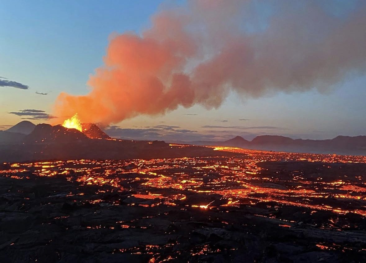 Wanderer auf einer Fagradalsfjall Vulkan Tour, die über schwarze Lavafelder in Island laufen